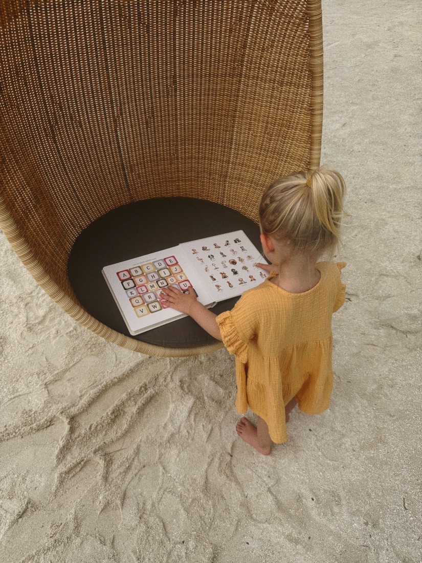 A small reader pointing at a page in the ABC Doodle Dogs book
